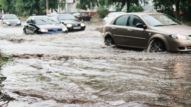 Cars driving down a flooded street