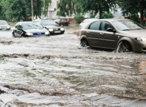 Cars driving down a flooded street