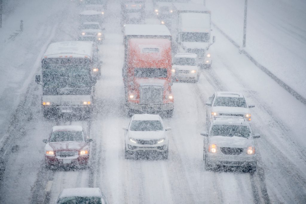 Trucks and cars driving down a highway in a snow storm