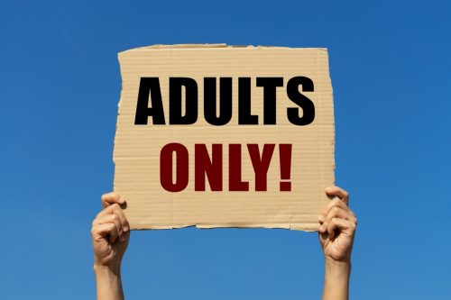 Adults only text on box paper held by 2 hands with isolated blue sky background