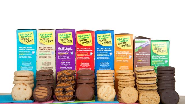 Girl Scout cookies in a row stacked in front of their colorful boxes