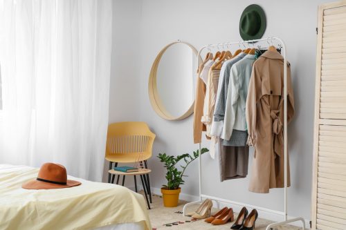 small bedroom ideas - hanging rack with clothes on it next to a bed