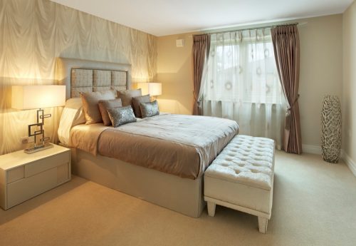 a lovely bedroom in a luxury new apartment with a colour mixture of browns and creams but warmed up by the bedside table lamps which have been turned on for the image. At the end of the bed is a large ottoman stool. Looking for a Bedroom image Then please see my other Bedrooms and related images by clicking on the Lightbox link below