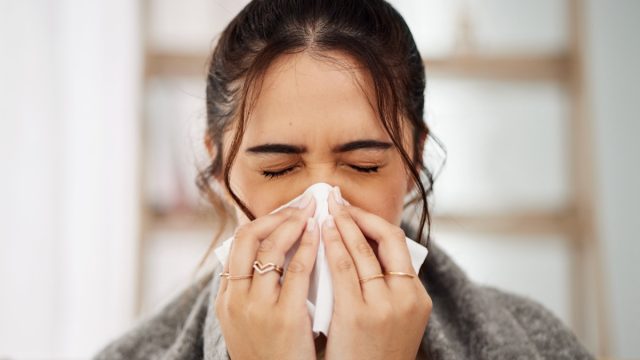 sick woman blowing nose
