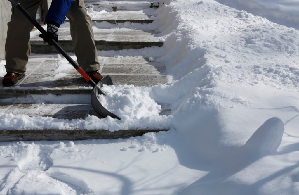 Man shoveling the show on bright winter day