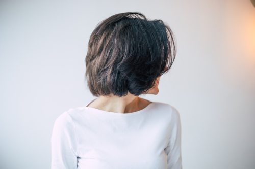 A young beautiful girl with short dark hair who turned away from the camera and shows her new hair styling.