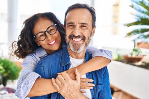 mature man and woman hugging and smiling at the camera