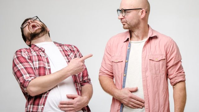 man laughing at yo mama jokes told at the expense of his friend