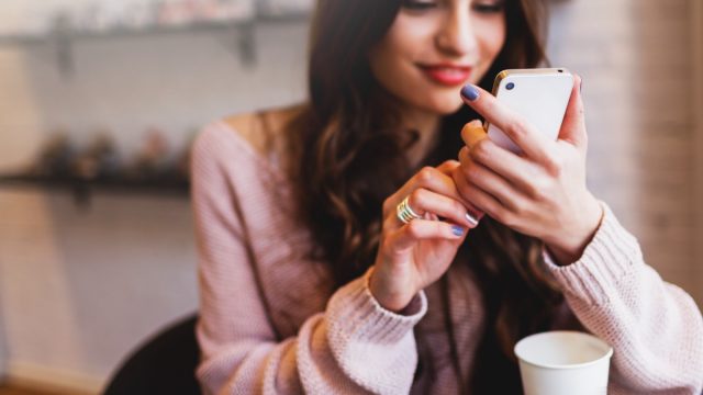 Attractive Woman wearing a pink blouse Texting while sitting at a coffee shop