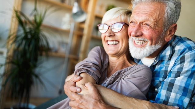 Mature husband and wife hugging and smiling at home