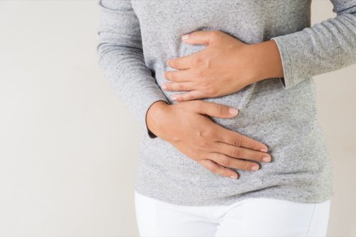 Young woman having painful stomachache. Chronic gastritis. Abdomen bloating concept.