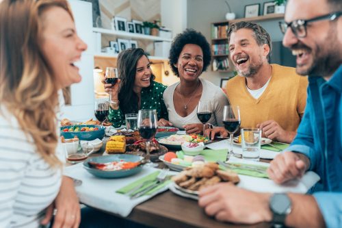 Young people dining and having fun drinking red wine together. Happy group of friends eating and enjoying each other company. Lunch and red wine at home