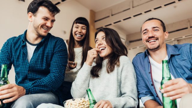 Two men and two women drinking beers and laughing while asking dirty would you rather questions