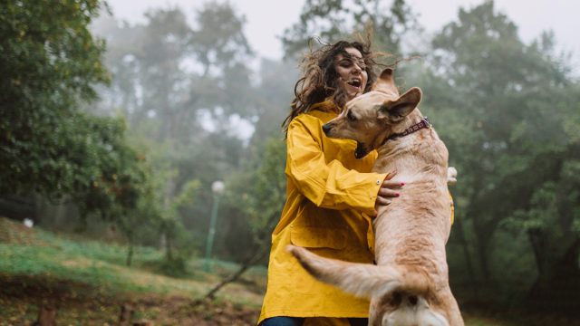 Young woman enjoying rainy day with her dog