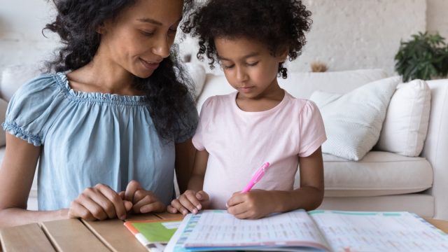mom help to cute little daughter with homework at home, preschool girl preparing for school do exercises, math tasks looks focused, close up. Studying, tutoring, education, development concept