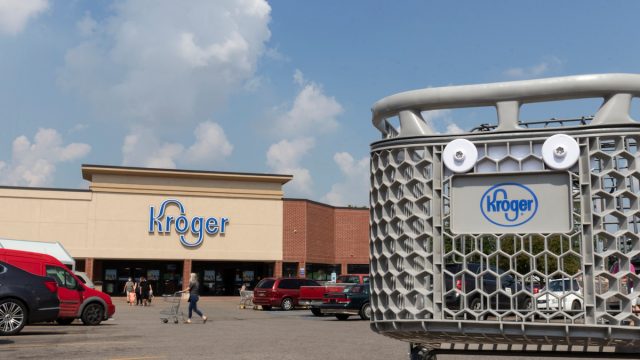 Close up of a Kroger shopping cart with a store in the background