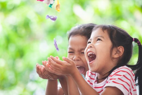 little boy and little girl holding out hands as someone drops candy into them