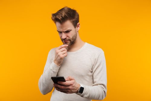 man looking confused as he looks at his phone