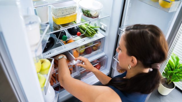 Women Looking For Food Inside Fridge In Kitchen