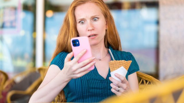 woman looking at her phone with a horrified expression