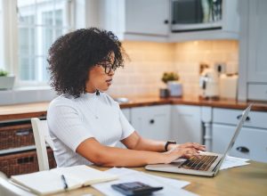 A woman filing her taxes or working from home in her kitchen using a laptop