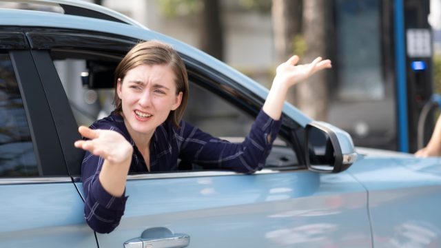 Annoyed woman leaning out of the passenger side of a car