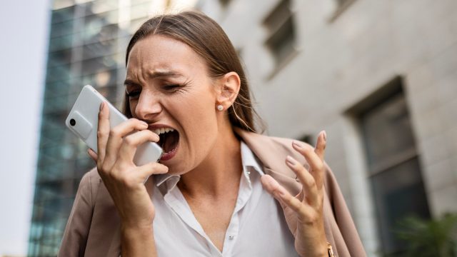 Angry businesswoman using phone shouting