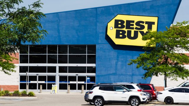 A Best Buy storefront with cars in the parking lot
