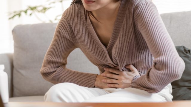 young woman with hand on stomach showing she's in pain