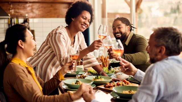 Group of friends toasting with rose wine at the dinner table