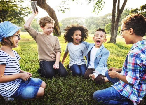 little kids sitting in a circle outside in a park sharing "fun facts about me"