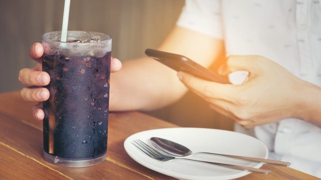 man at a restaurant drinking a diet soda