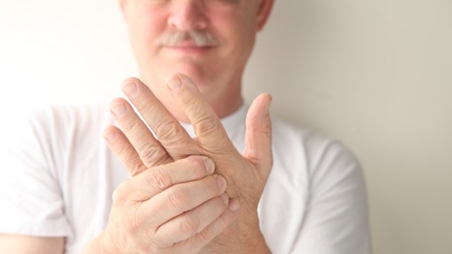 man holding one hand with the other and looking concerned
