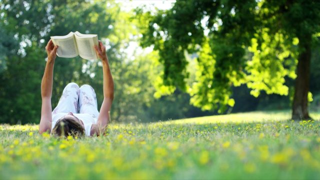 woman reading a book in the grass on a warm spring day