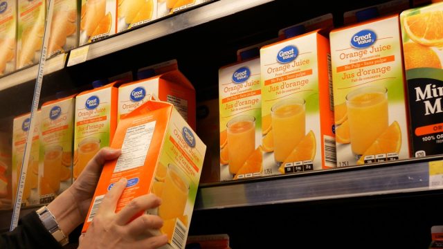 Motion of woman buying great value orange juice inside Walmart store