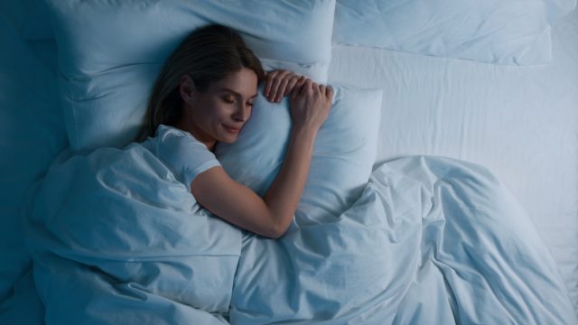 Woman sleeping in bed at night, above view. Space for text