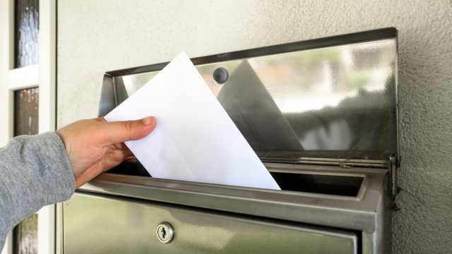 hand putting mail in mailbox