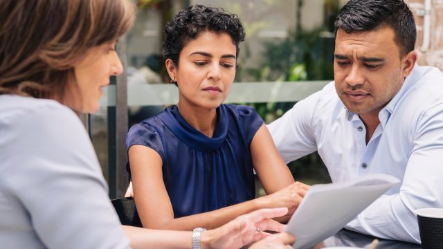 A couple speaking with a financial planner with serious looks on their faces