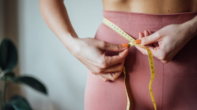 woman taking waist measurements