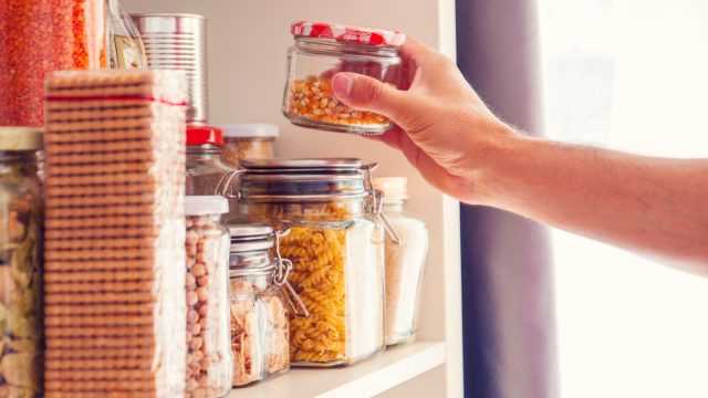 A Man Takes or Places Glass Jars Filled With Legumes From A Shelf In The Pantry