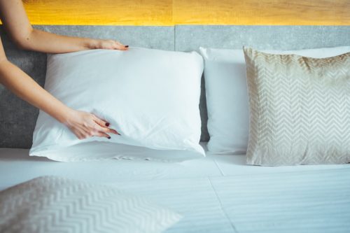 Maid making bed in hotel room. Female hands corrected pillow on the bed. Concept on preparation of bed in a hotel room or at home. Maid Making Bed