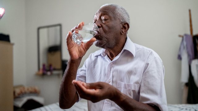 A senior man taking medicine with a glass of water