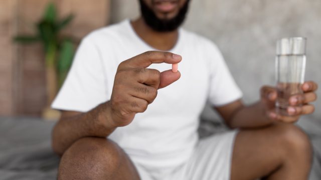 man getting ready for bed holding melatonin supplement