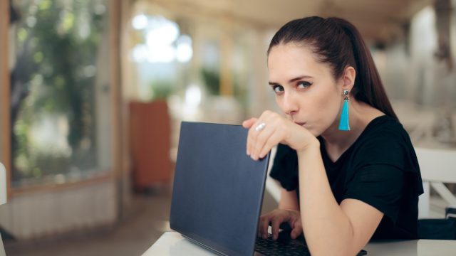 Young woman in a cafe hiding her laptop screen