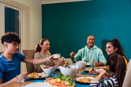 A family of five sitting at the table in their home in the North East of England enjoying a family meal together and catching up as a family over dinner.