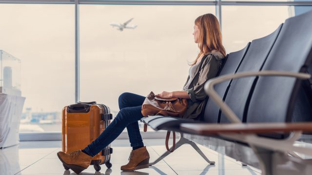 A woman sitting in an airport with her luggage waiting to board a flight