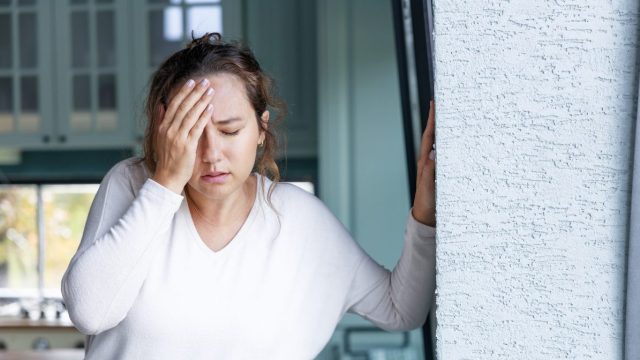 A woman holding her head in pain, possibly with symptoms of a stroke