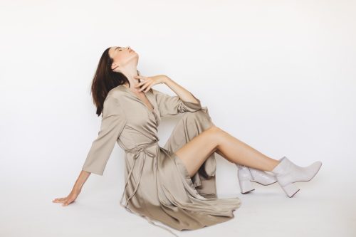 Woman wear long silk kimono, summer kimono, silk loungewear. Natural bathrobe. Details of minimalist look. Woman dressed in fashionable beige wrap around midi dress. Woman sitting on the floor.