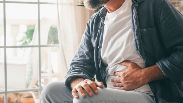Man suffering with severe stomach pain sitting at home