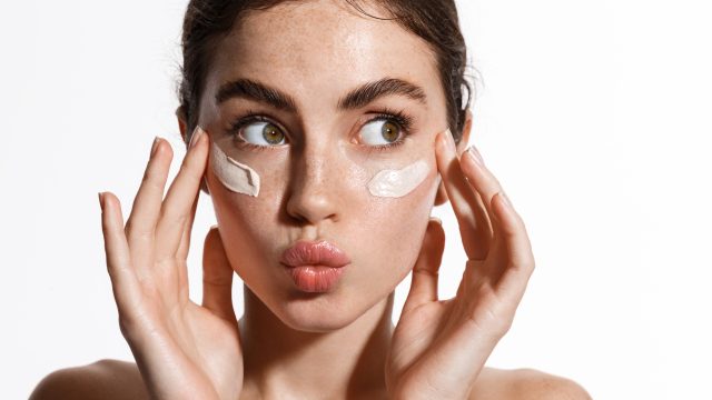 Closeup of young woman putting on sunscreen